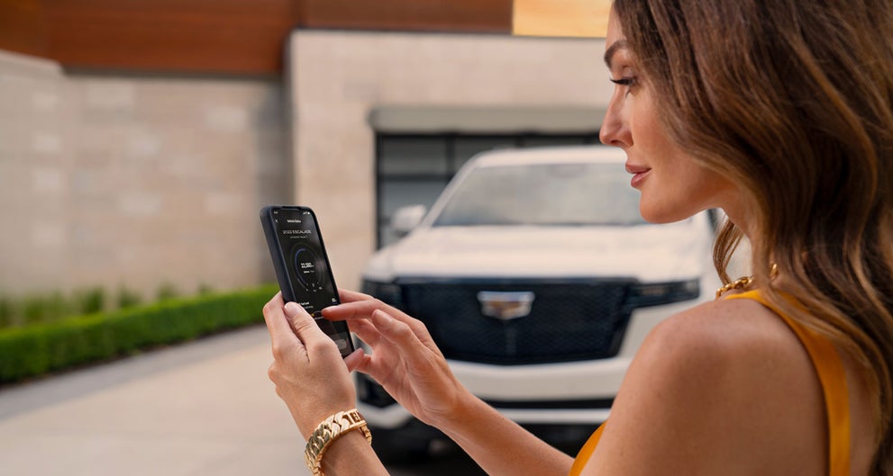 lady checking her mobile with a Cadillac vehicle background | Dublin Cadillac in Dublin CA