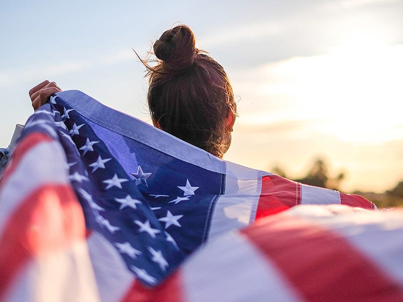 A women holding American flag at sunset.
