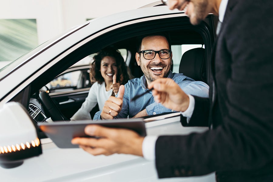 A salesperson talking with customer who seats inside the car